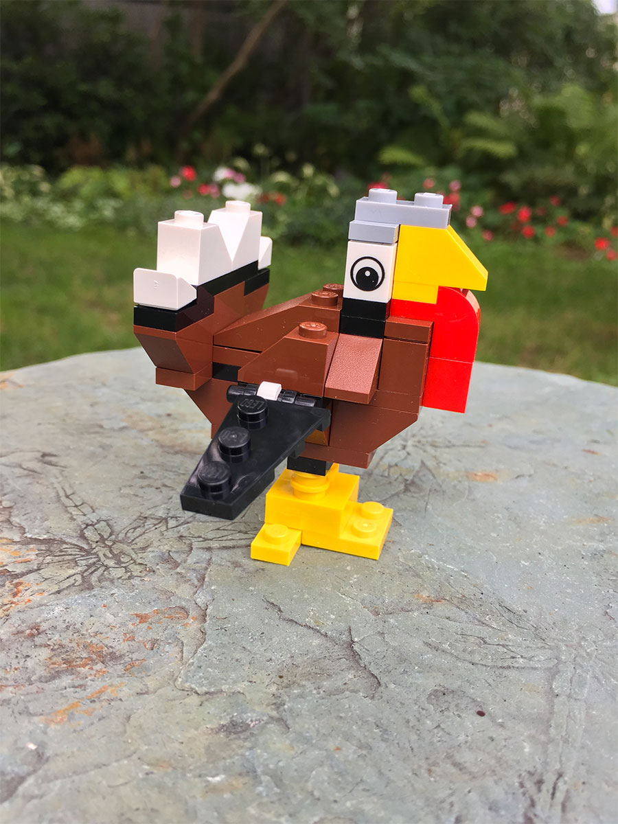 A brown turkey made of LEGO bricks sits on a table outside.